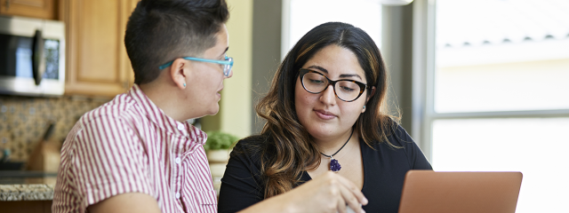 Two people at home with laptop, reviewing bills and receipts